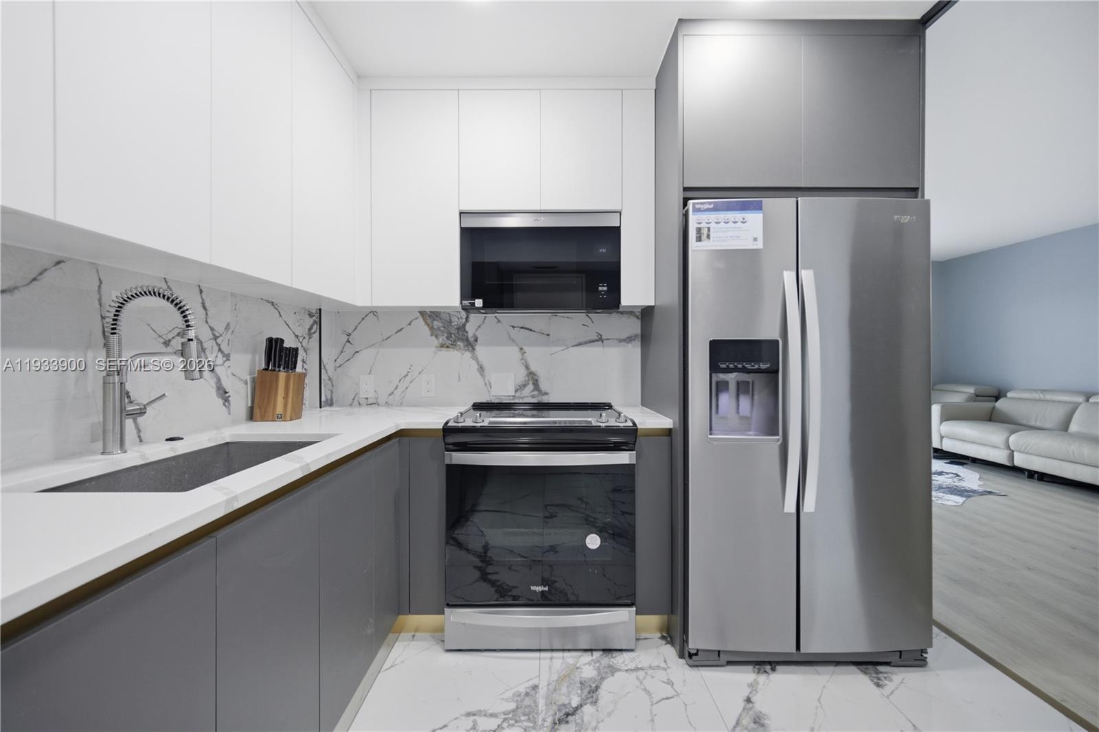 A modern kitchen features gray lower cabinets, white upper cabinets, and marble-patterned countertops and flooring — 4200 Hillcrest Dr # 802, Hollywood FL 33021, HOLLYWOOD, FL