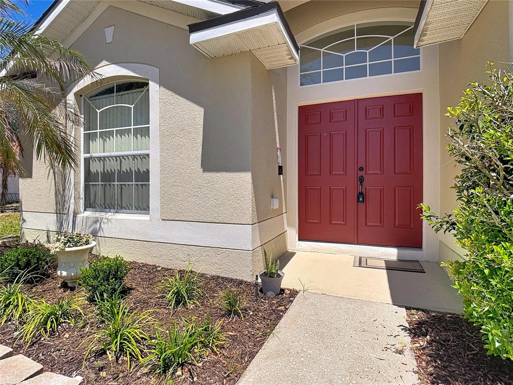 The exterior of a house features a red double door entrance and a front garden — 1029 BRAYTON LANE, DAVENPORT, FL