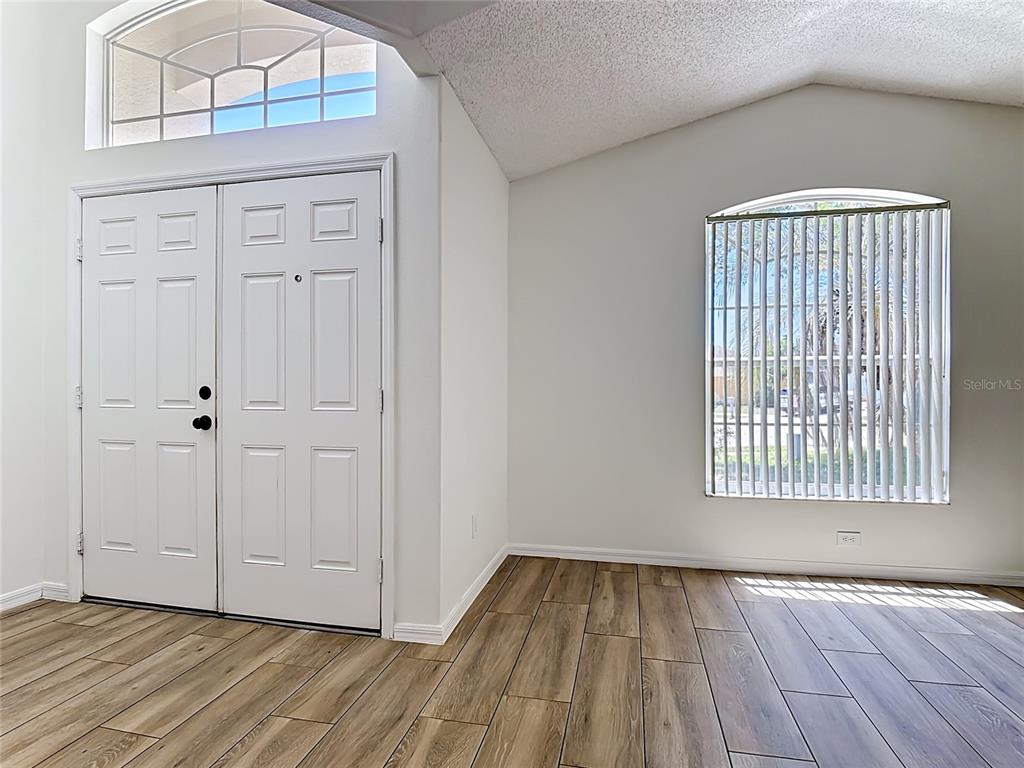 An entryway features double doors, a vaulted ceiling, a large arched window, and wood-look flooring — 1029 BRAYTON LANE, DAVENPORT, FL