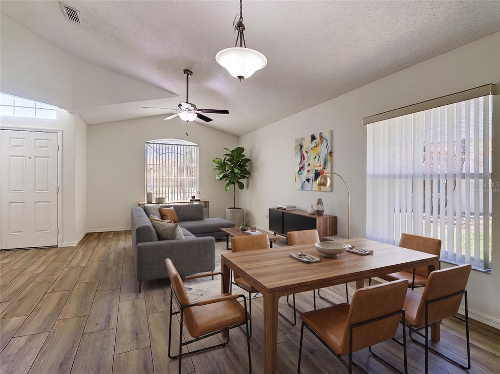A living and dining area features wood-look tile flooring, a vaulted ceiling, and modern furniture — 1029 BRAYTON LANE, DAVENPORT, FL