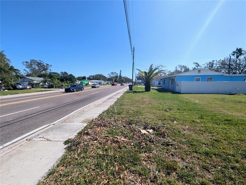 A view of a street with a blue house and a white fence — 3990 54TH AVENUE N, ST PETERSBURG, FL