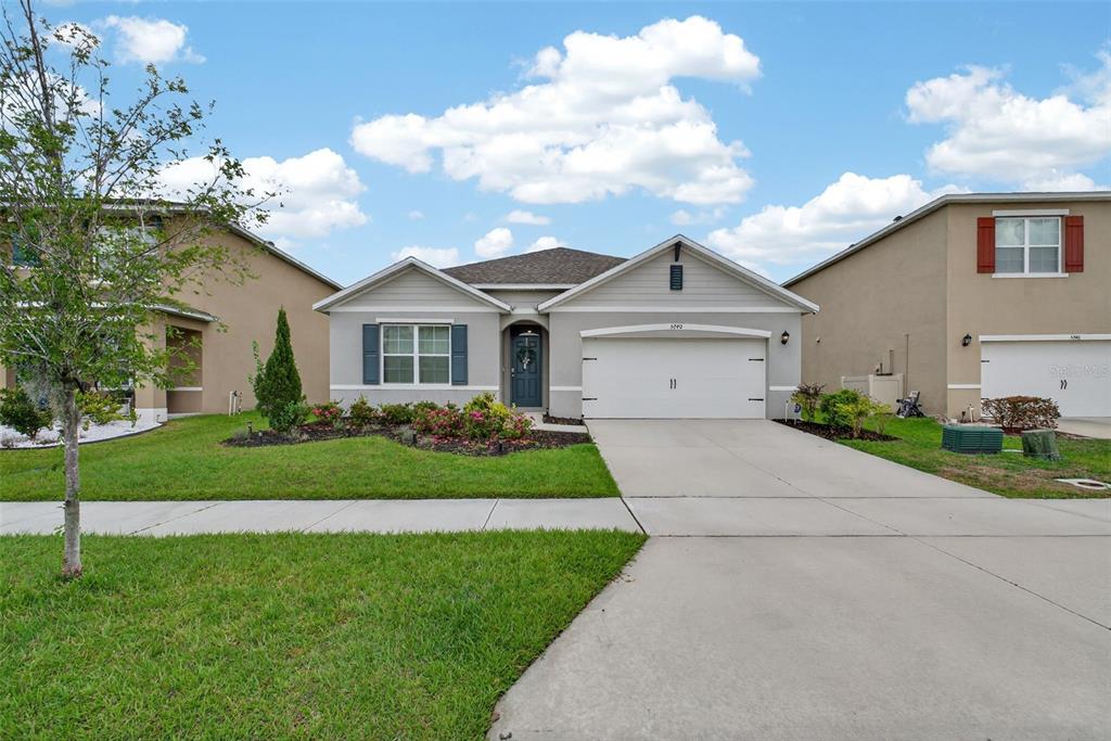 A single-story suburban house with a gray exterior, a two-car garage, and a front lawn — 5740 GREY GRANITE WAY, LAKELAND, FL