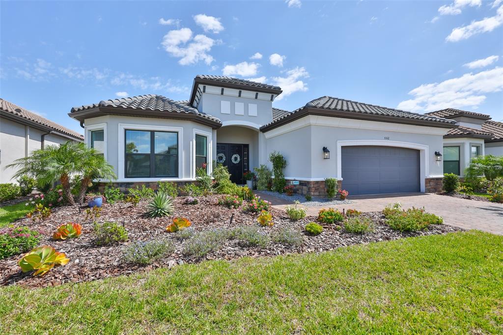 A single-story house with a gray stucco exterior, tile roof, and a paved driveway — 5512 CASERTA COURT, PALMETTO, FL