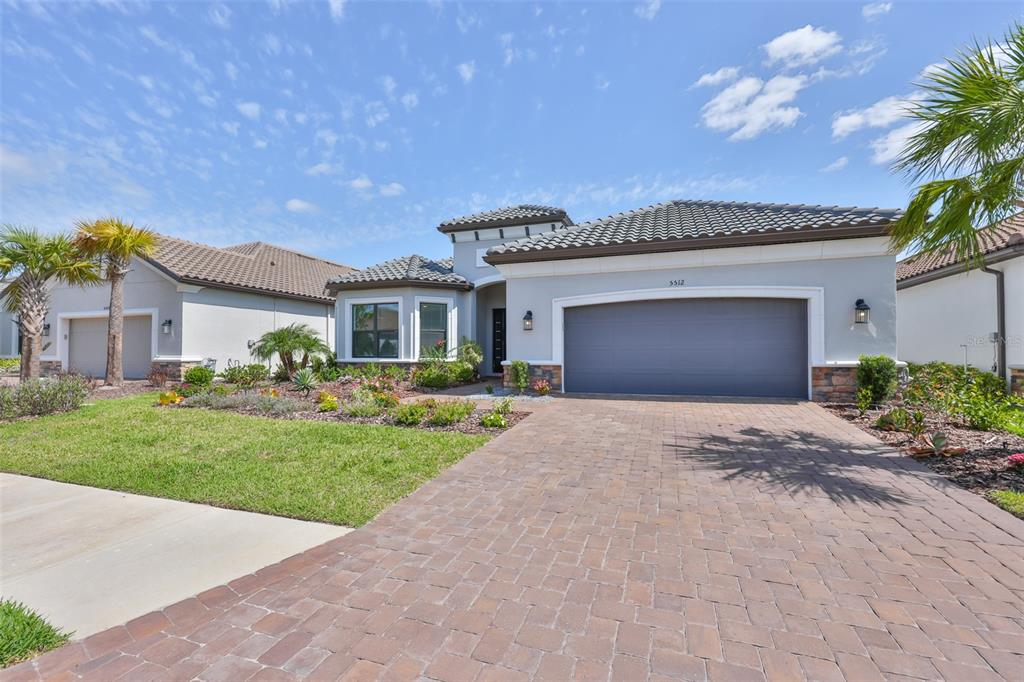 A single-story house with a gray garage, stone accents, and a paved driveway — 5512 CASERTA COURT, PALMETTO, FL