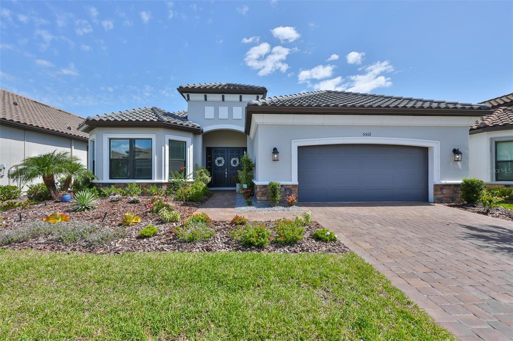 A single-story house with a gray garage, tile roof, and landscaped front yard — 5512 CASERTA COURT, PALMETTO, FL