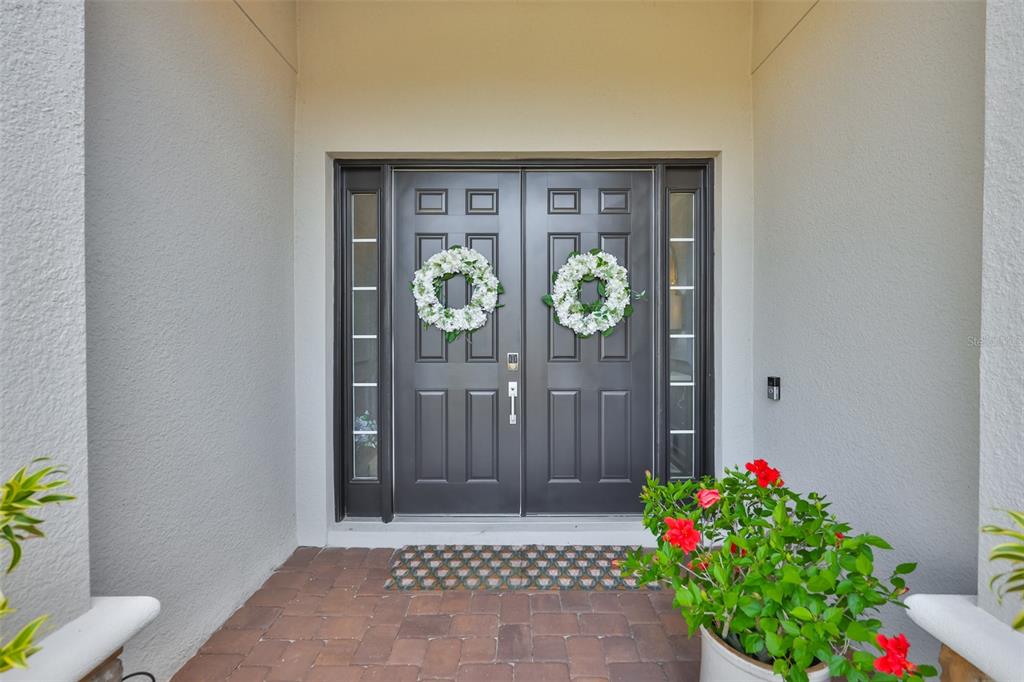 A front entryway features a dark double door with white floral wreaths and brick flooring — 5512 CASERTA COURT, PALMETTO, FL