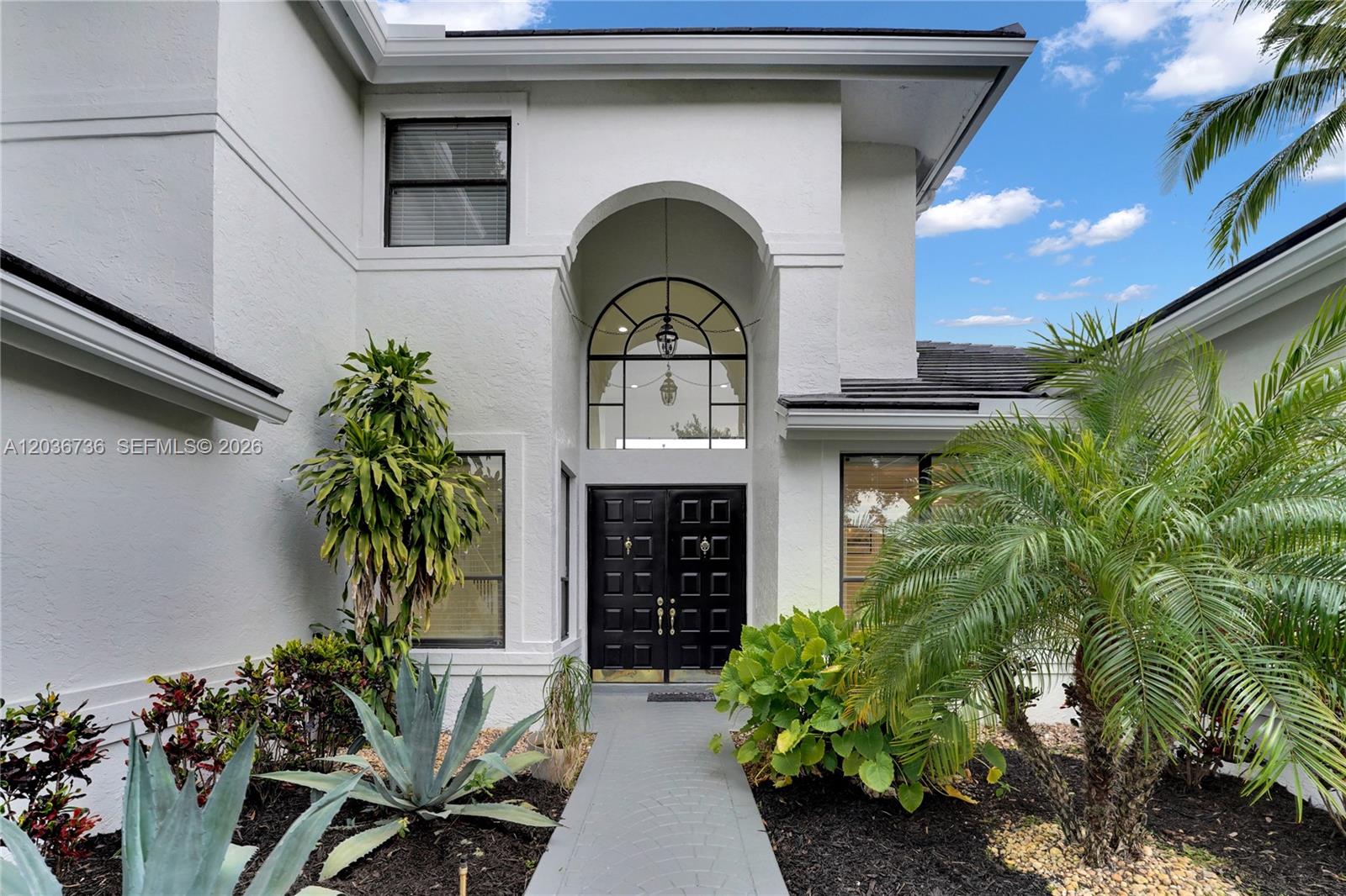 The exterior of a white house features a black double door under an arched window — 22281 Tupelo Pl, Boca Raton FL 33428, BOCA RATON, FL