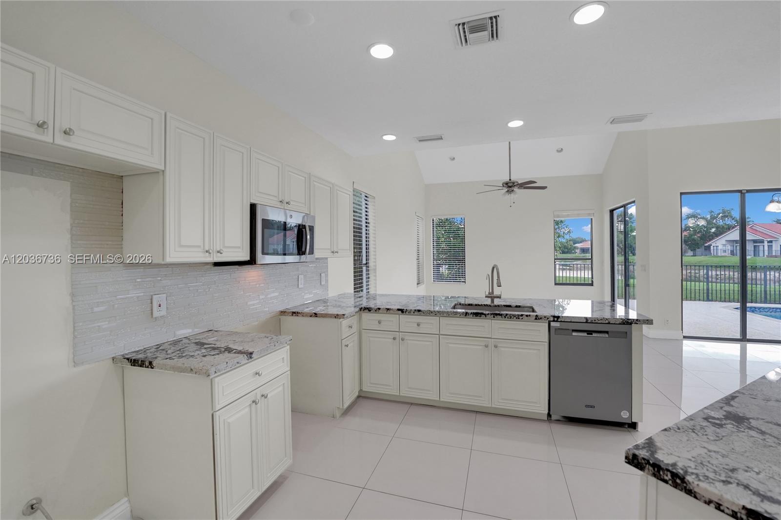 A kitchen features white cabinets, granite countertops, stainless steel appliances, and tile flooring — 22281 Tupelo Pl, Boca Raton FL 33428, BOCA RATON, FL