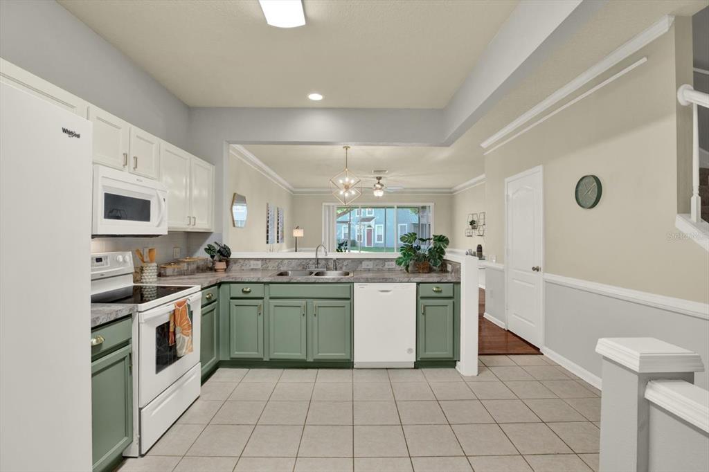 A kitchen with green lower cabinets, white upper cabinets, and a pass-through to the living area — 2733 CONCH HOLLOW DRIVE, BRANDON, FL