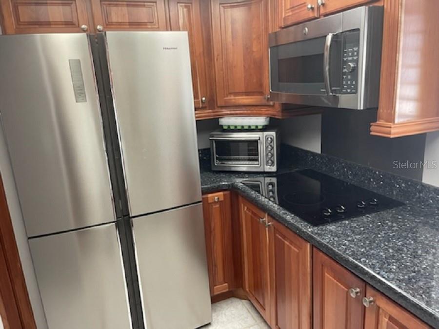 A kitchen features wood cabinets, stainless steel appliances, and dark granite countertops — 90 S HIGHLAND AVENUE UNIT 1, TARPON SPRINGS, FL