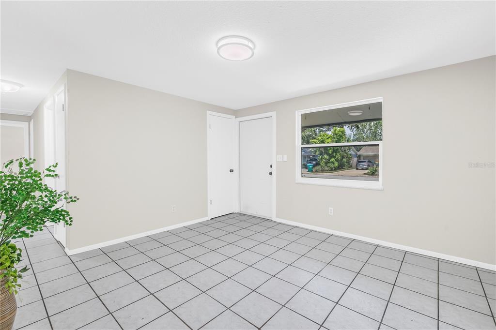 A room with light gray walls, white trim, and gray tiled flooring — 10920 111TH STREET, LARGO, FL