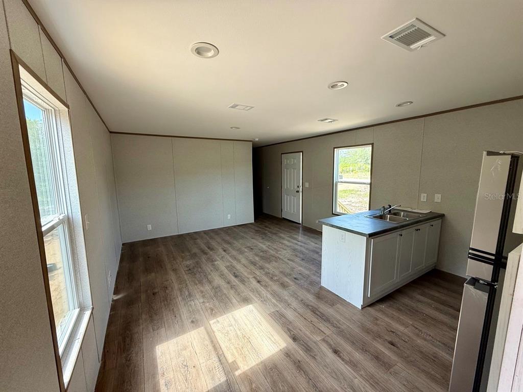 An open-concept kitchen and living area features wood-look flooring, recessed lighting, and a kitchen island — TBD NE 115TH AVENUE, WILLISTON, FL