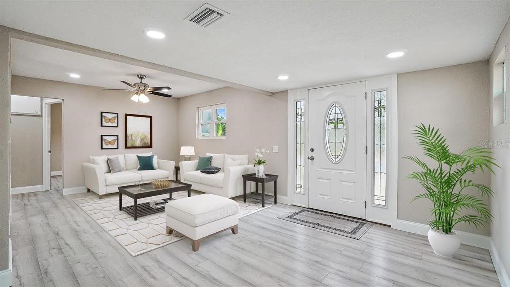 A living room features light wood-look flooring, white sofas, a coffee table, and a front door — 5135 NEWTON AVENUE S, GULFPORT, FL
