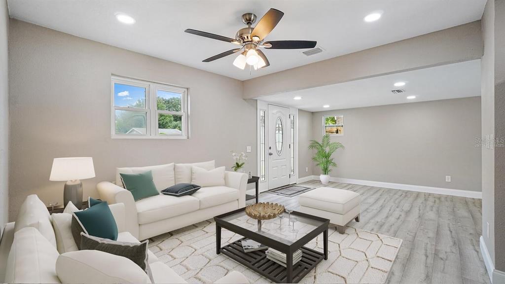 A living room features a white sofa, coffee table, ceiling fan, and light-colored flooring — 5135 NEWTON AVENUE S, GULFPORT, FL