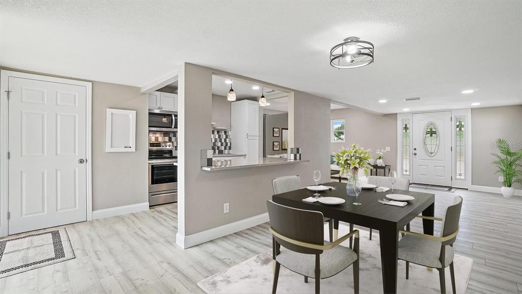 A dining area features a dark table, light wood-look flooring, and an open kitchen pass-through — 5135 NEWTON AVENUE S, GULFPORT, FL