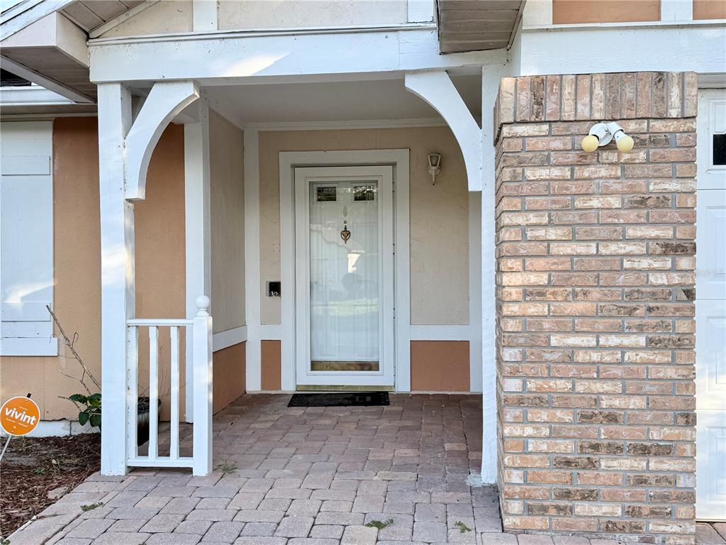 A covered front porch features a white door, brick pillar, and paver walkway — 1512 ISON LANE, OCOEE, FL