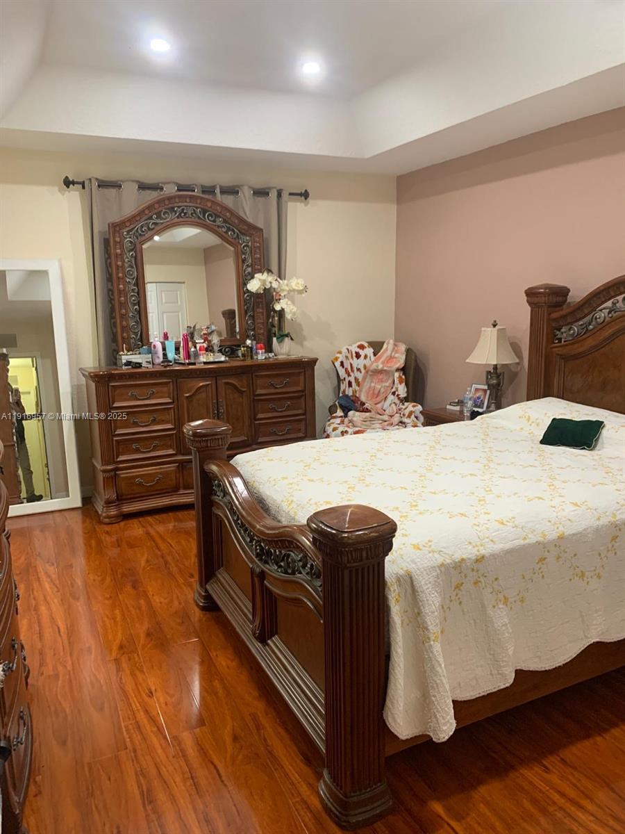 A bedroom features a wooden bed frame, a matching dresser with a mirror, and hardwood floors — 462 SE 23rd Dr, Homestead FL 33033, HOMESTEAD, FL