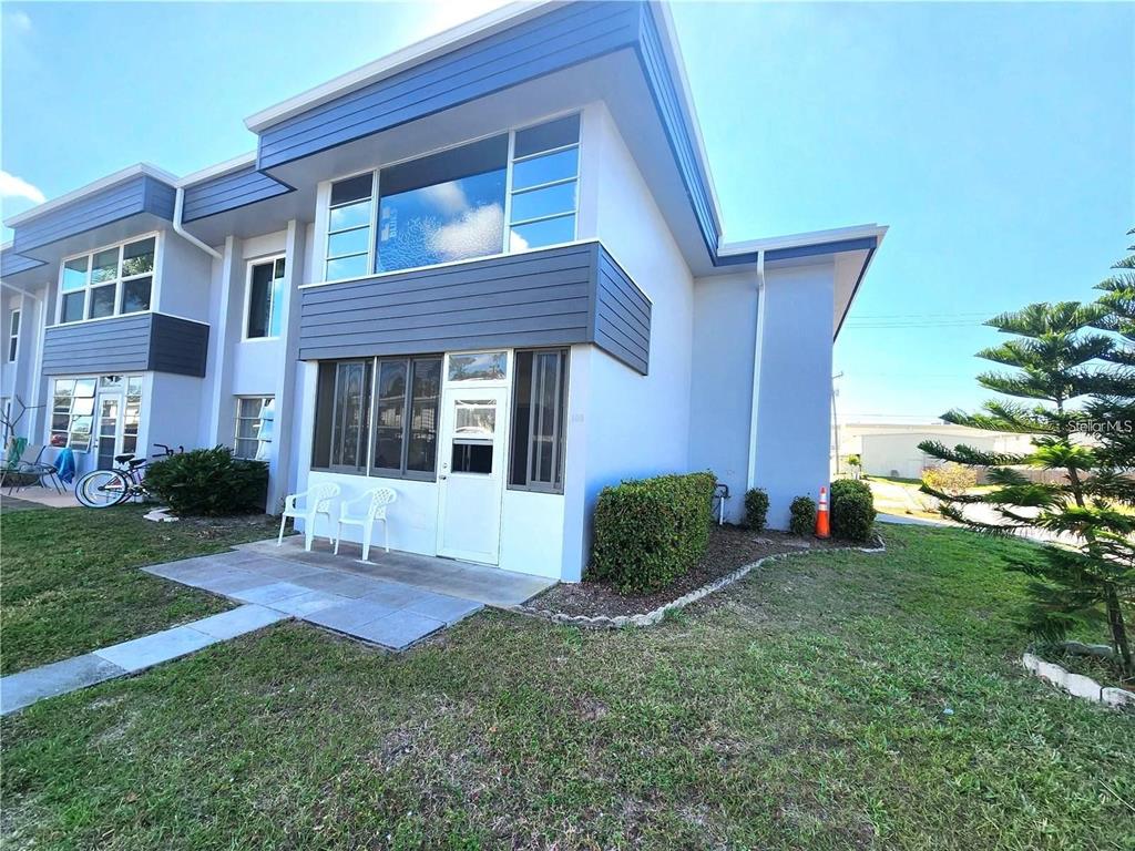 A two-story townhouse exterior with a screened-in patio and blue horizontal siding accents — 21320 BRINSON AVENUE UNIT 109, PORT CHARLOTTE, FL