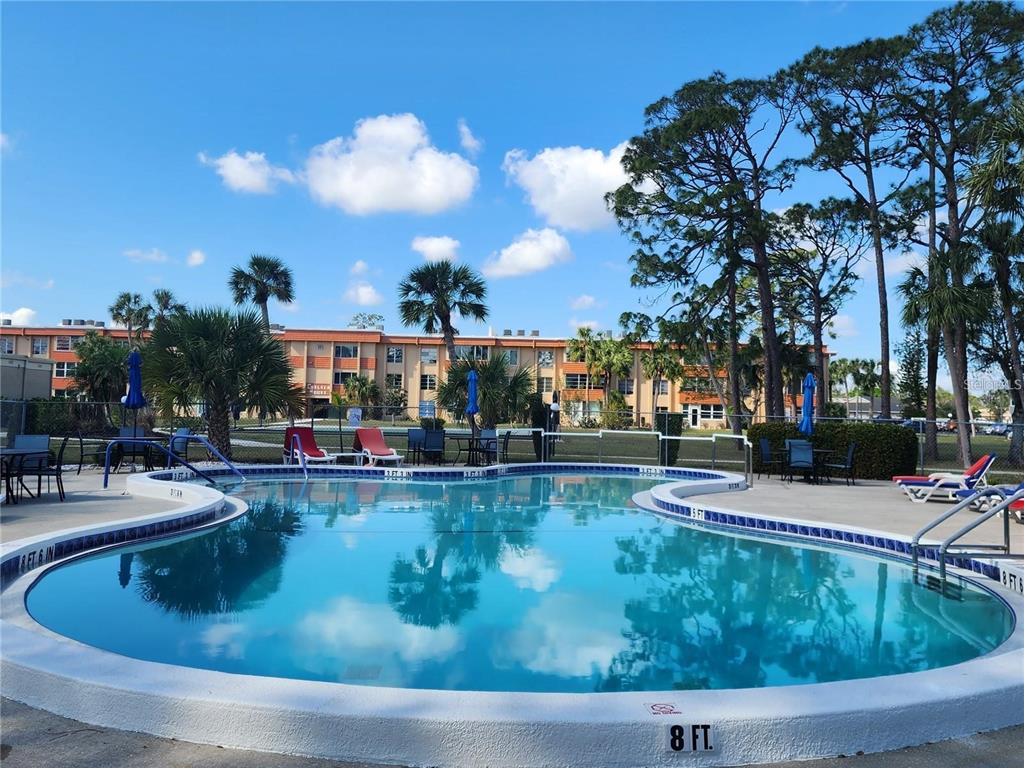 A swimming pool with a depth marker sits in front of a multi-story apartment building — 21320 BRINSON AVENUE UNIT 109, PORT CHARLOTTE, FL
