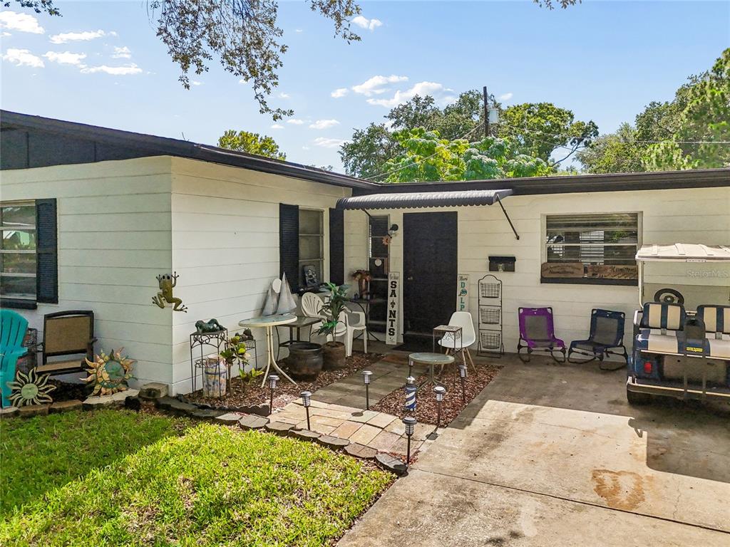 A white, single-story house exterior features a concrete patio, a golf cart, and landscaping — 7846 12TH STREET N, ST PETERSBURG, FL