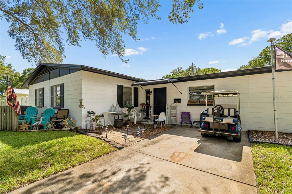 A single-story white house with a concrete driveway, a golf cart, and a front patio — 7846 12TH STREET N, ST PETERSBURG, FL