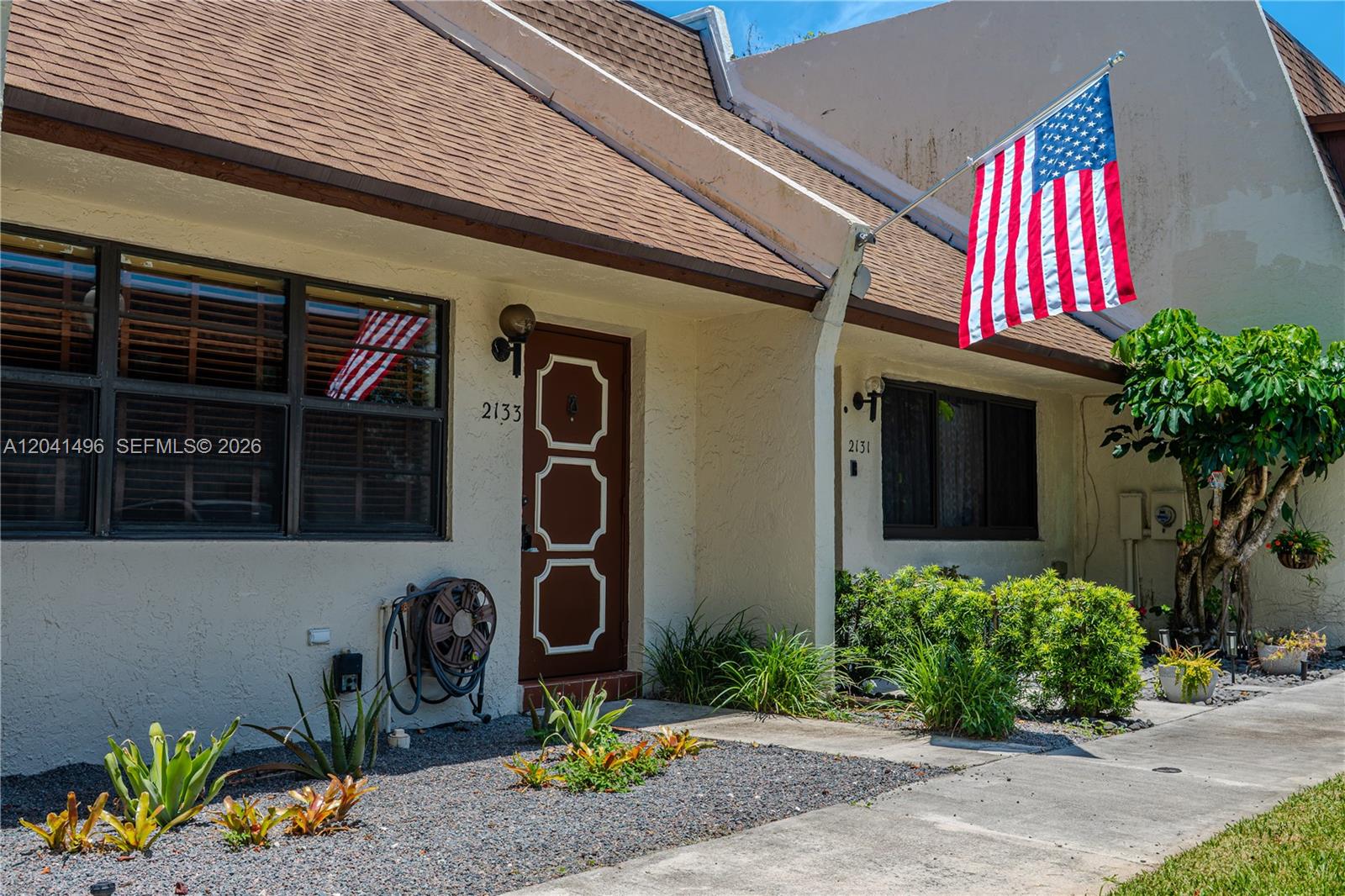 The exterior of a single-story residential building features a brown roof, stucco walls, and an American flag — 2133 N 14th Ave, Hollywood FL 33020, HOLLYWOOD, FL