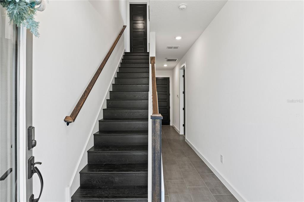A staircase with dark wood steps and a wooden handrail leads to a hallway — 12468 KOSHIBA ALLEY, ORLANDO, FL