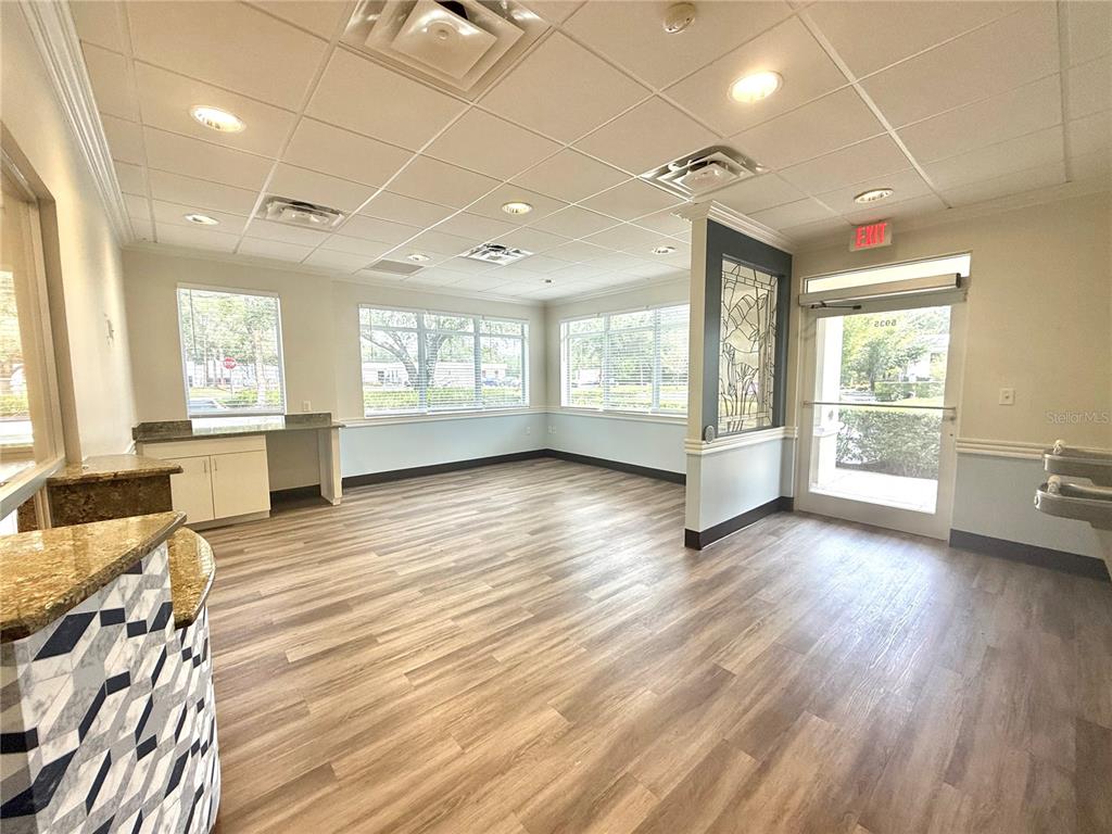 A bright office lobby features wood-look flooring, drop ceilings, a reception desk, and glass doors — 5935 WEBB ROAD, TAMPA, FL