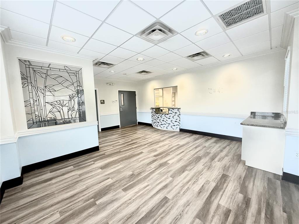 An office interior features wood-look flooring, a drop ceiling, and a decorative stained-glass wall panel — 5935 WEBB ROAD, TAMPA, FL