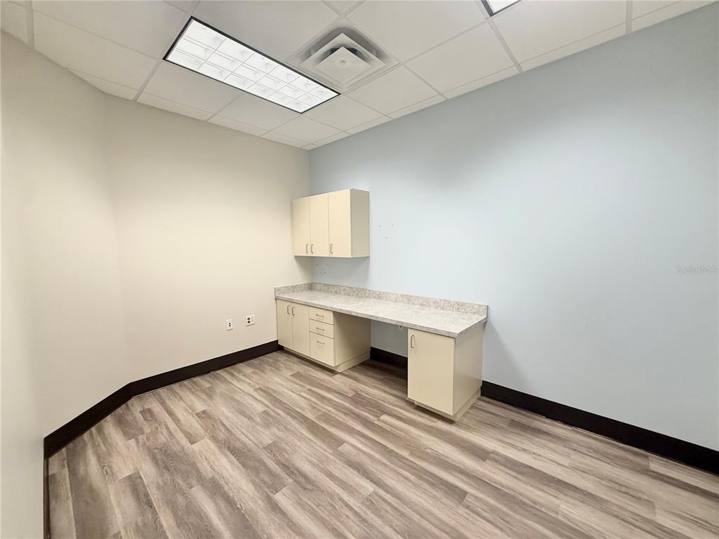 An office room features light-colored cabinetry, a countertop, and wood-look flooring under a drop ceiling — 5935 WEBB ROAD, TAMPA, FL