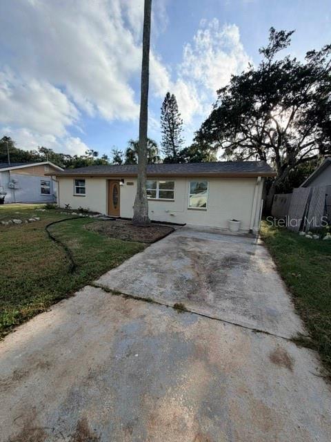 A single-story house with a concrete driveway, a palm tree, and a light-colored exterior — 7317 OELSNER STREET, NEW PORT RICHEY, FL