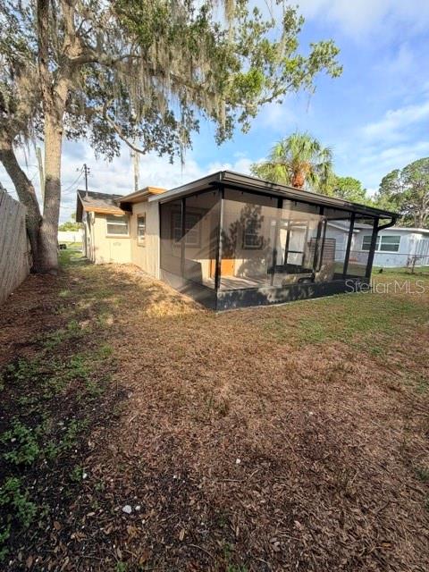 A house with a large screened-in porch and a tree in the backyard — 7317 OELSNER STREET, NEW PORT RICHEY, FL