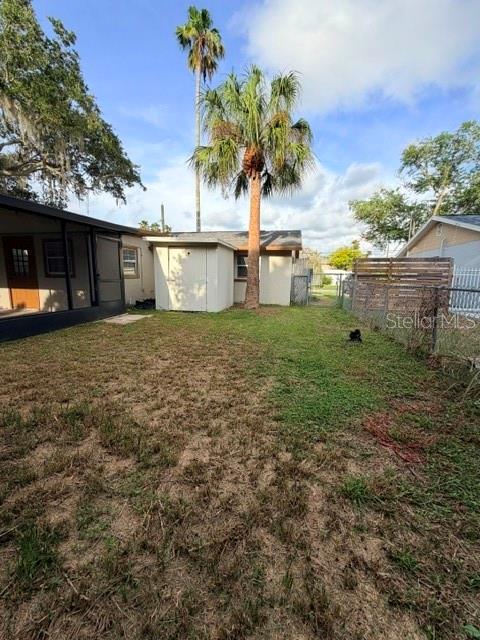 A backyard features a small shed, a tall palm tree, and a covered patio area — 7317 OELSNER STREET, NEW PORT RICHEY, FL