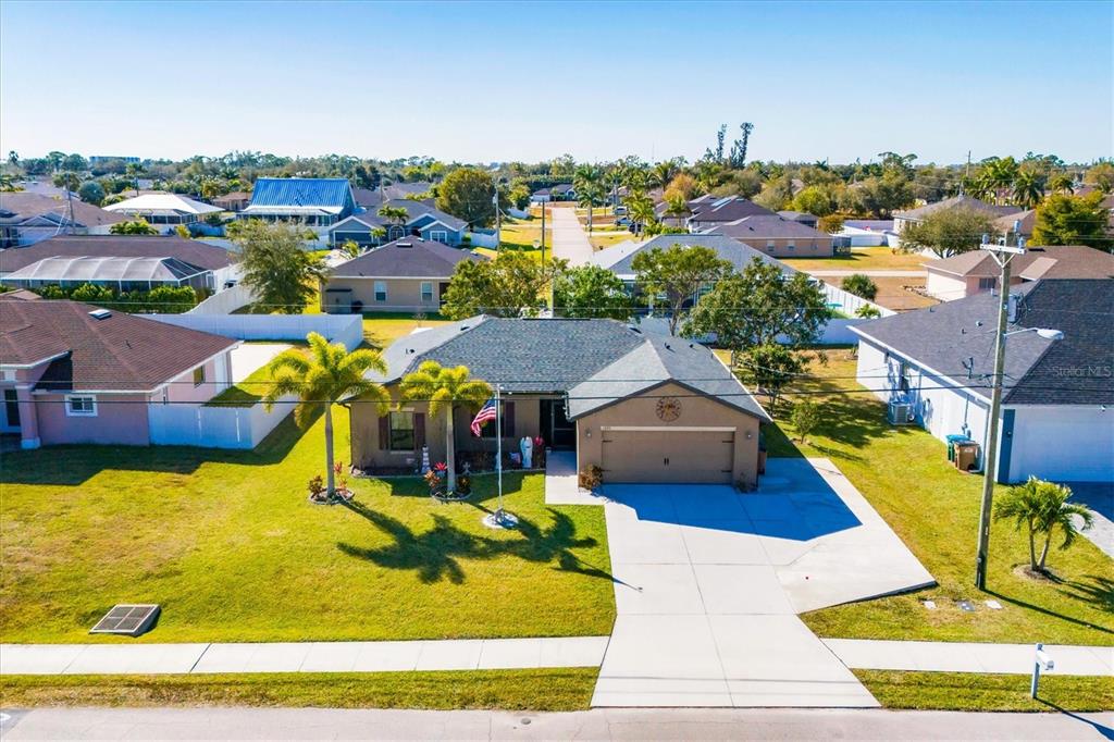 An aerial view shows a single-story suburban house with a tan exterior and a two-car garage — 1826 SW TRAFALGAR PARKWAY, CAPE CORAL, FL