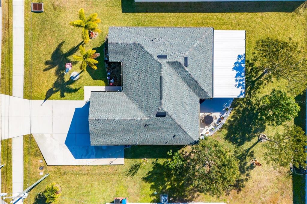 An aerial view shows a house with a gray shingled roof, driveway, and backyard patio — 1826 SW TRAFALGAR PARKWAY, CAPE CORAL, FL