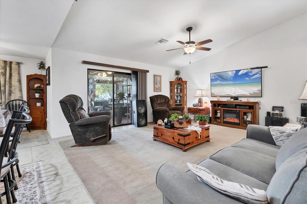 A living room features a gray sofa, two recliners, a coffee table, and a television — 1826 SW TRAFALGAR PARKWAY, CAPE CORAL, FL