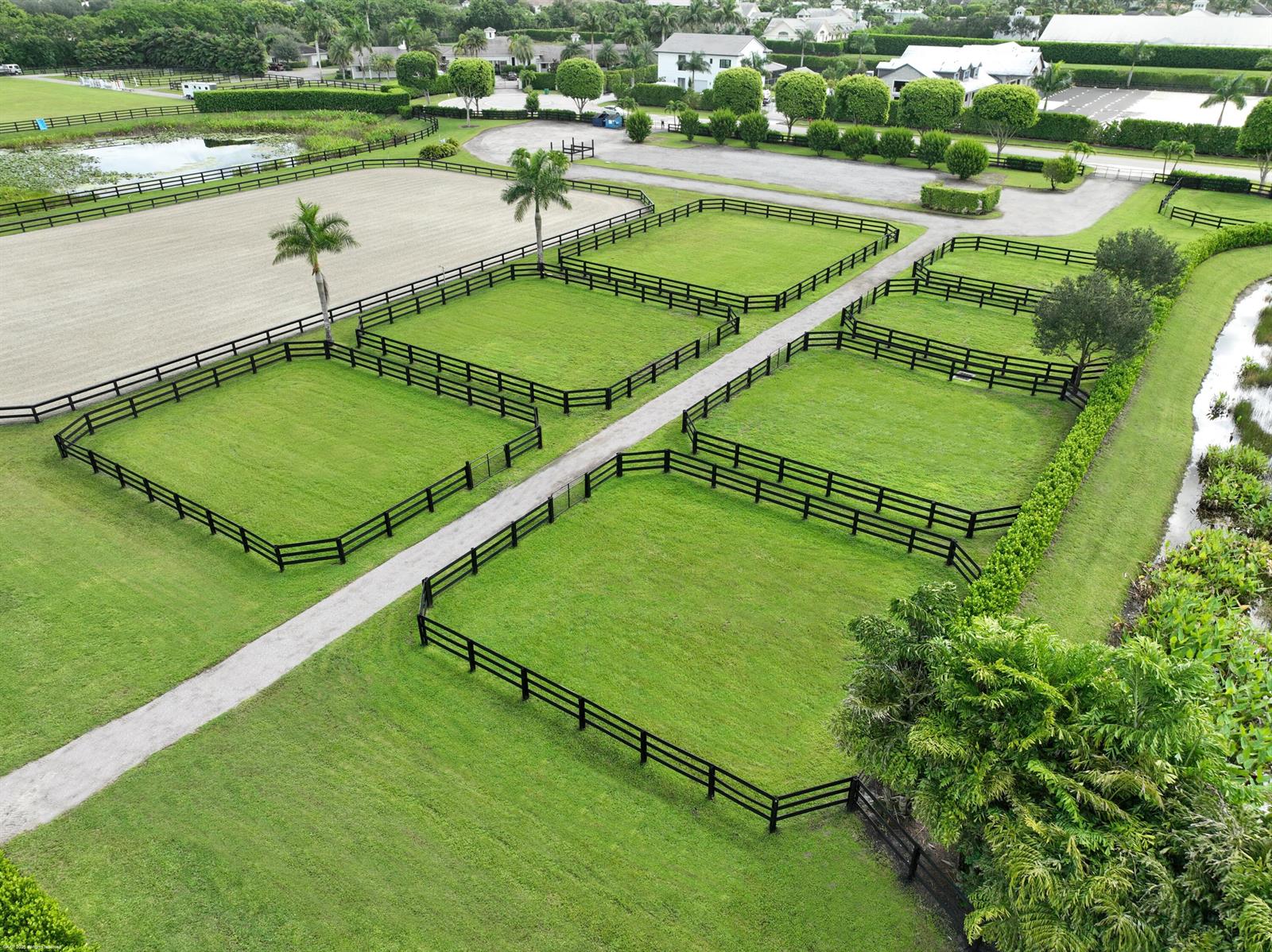 An aerial view shows fenced grass paddocks and a dirt path on a horse farm — 3899 Shutterfly Way, Wellington FL 33414, WELLINGTON, FL