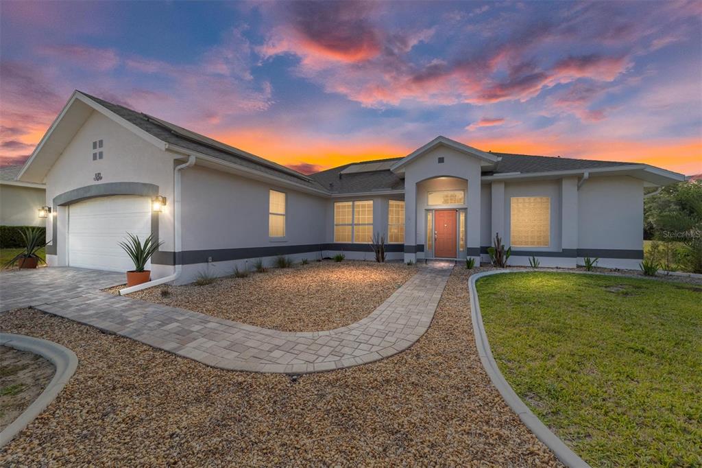 A single-story house with a paved walkway, gravel landscaping, and a two-car garage at sunset — 4543 N JADEMOOR DRIVE, BEVERLY HILLS, FL
