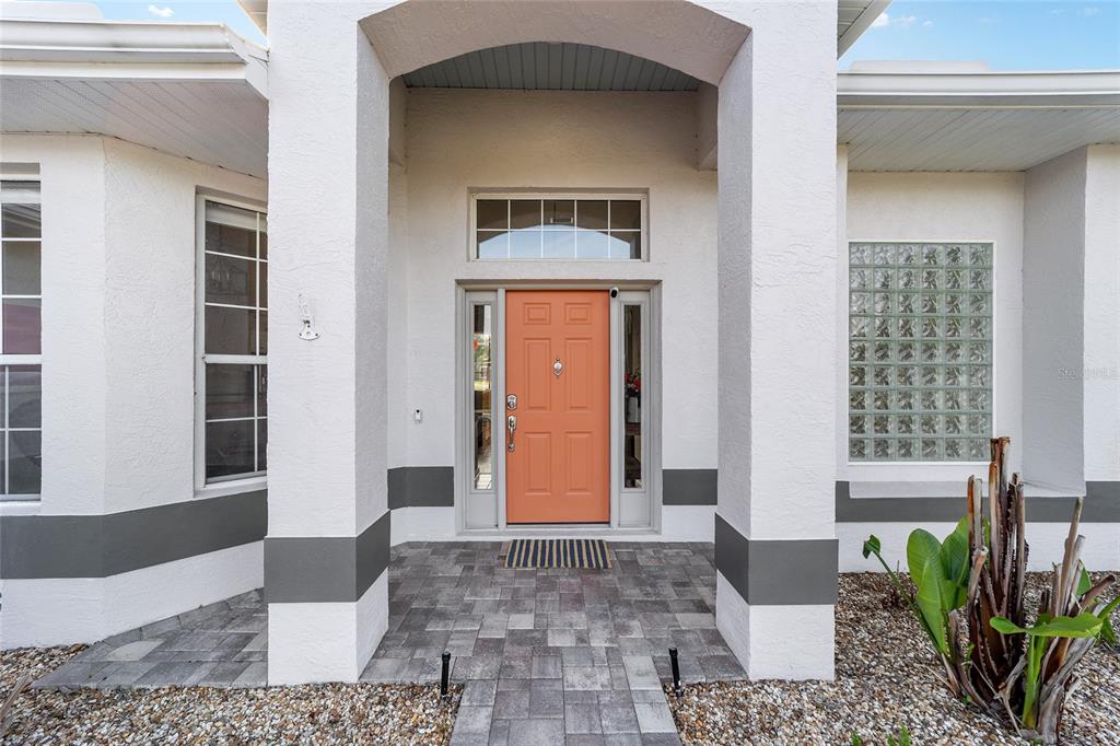 The front entrance of a house features a peach-colored door, glass block windows, and columns — 4543 N JADEMOOR DRIVE, BEVERLY HILLS, FL