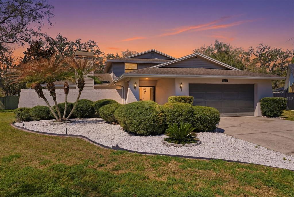 A two-story house with a gray garage, white rock landscaping, and palm trees at sunset — 12935 RAIN FOREST STREET, TEMPLE TERRACE, FL