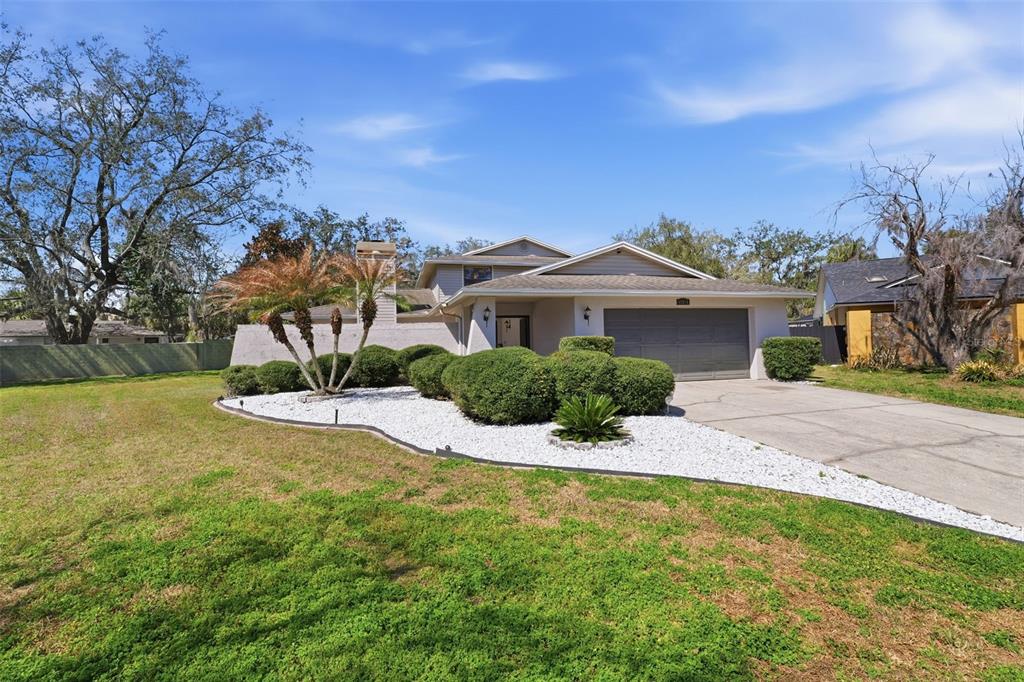 A single-story house with a two-car garage, white rock landscaping, and a large front lawn — 12935 RAIN FOREST STREET, TEMPLE TERRACE, FL