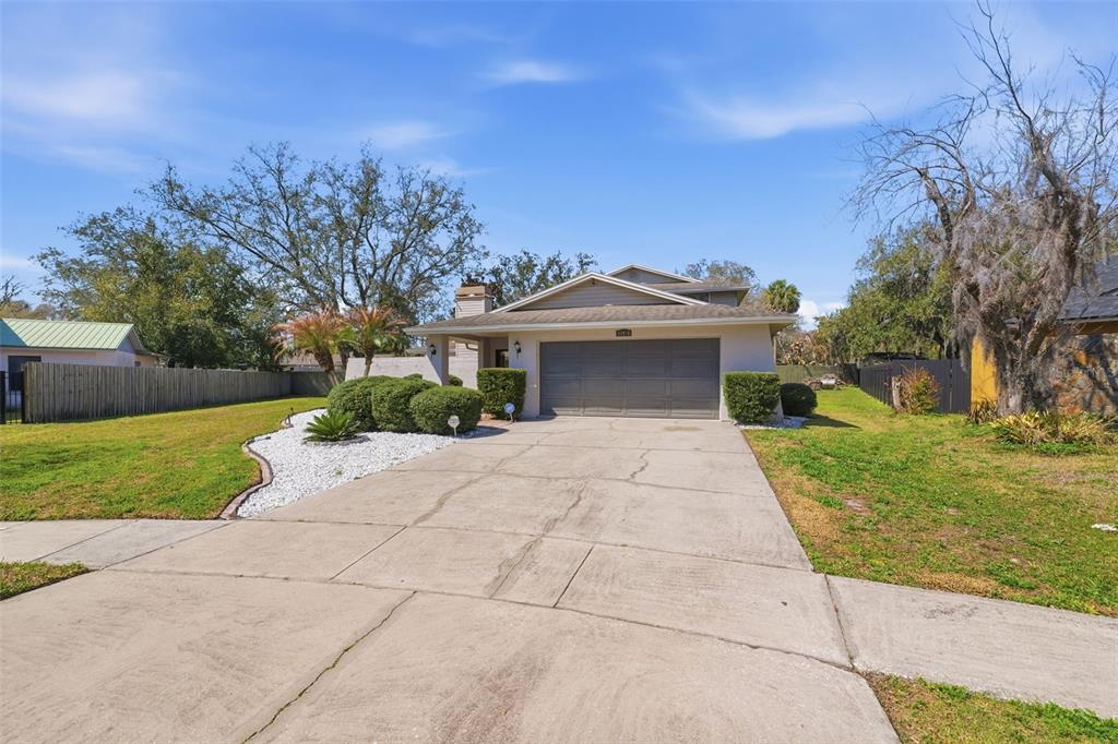 A single-story house with a gray garage, a concrete driveway, and a landscaped front yard — 12935 RAIN FOREST STREET, TEMPLE TERRACE, FL