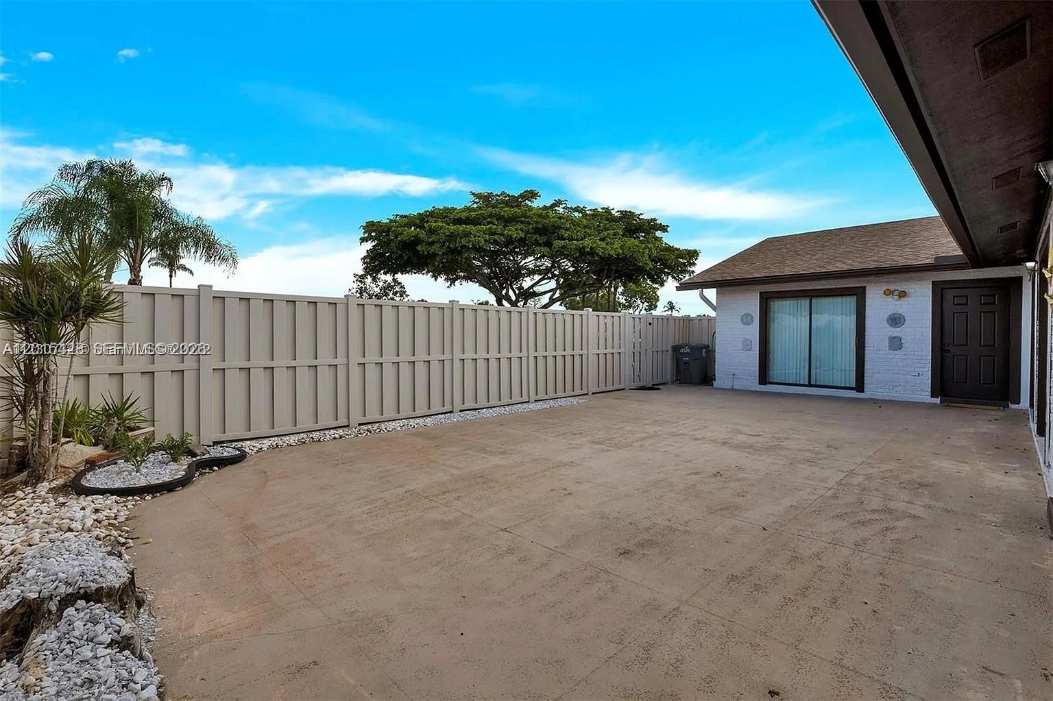 A concrete patio area is enclosed by a tall vinyl fence next to a house — 9892 Boca Gardens Pkwy # A, Boca Raton FL 33496, BOCA RATON, FL