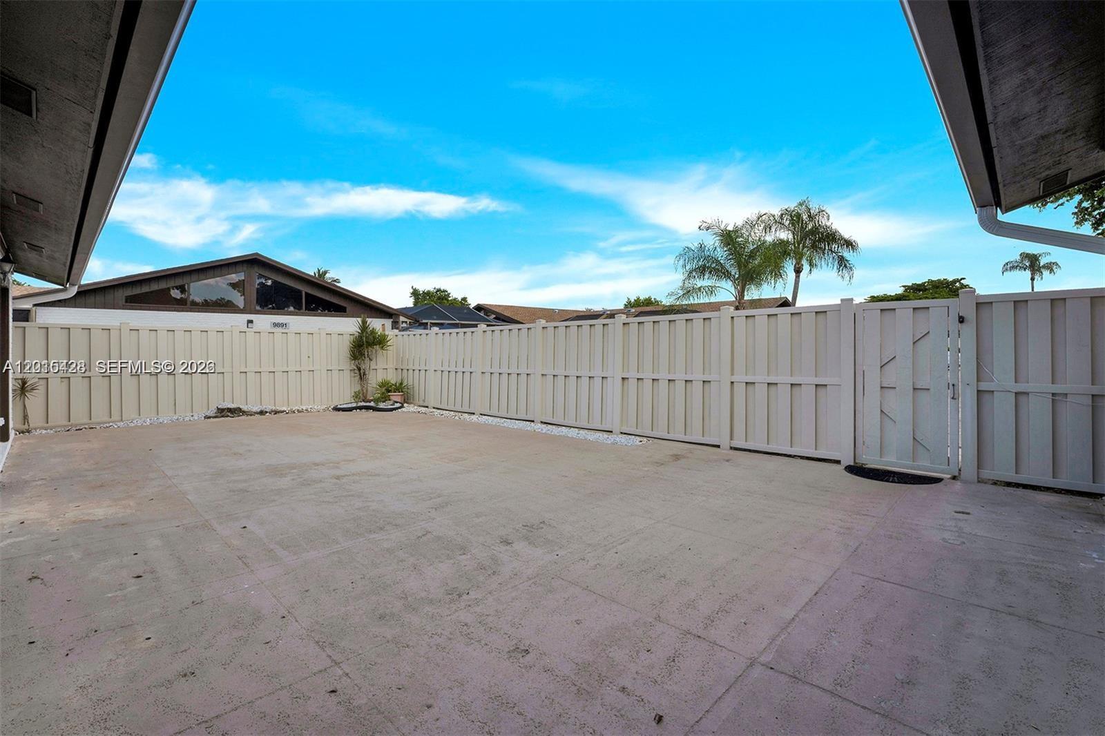 A concrete patio is enclosed by a tall white vinyl fence under a blue sky — 9892 Boca Gardens Pkwy # A, Boca Raton FL 33496, BOCA RATON, FL