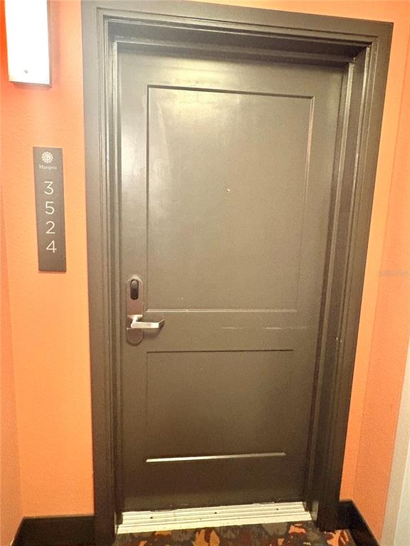 A dark gray door with a silver handle is set against an orange wall — 14501 GROVE RESORT AVENUE UNIT 3524, WINTER GARDEN, FL