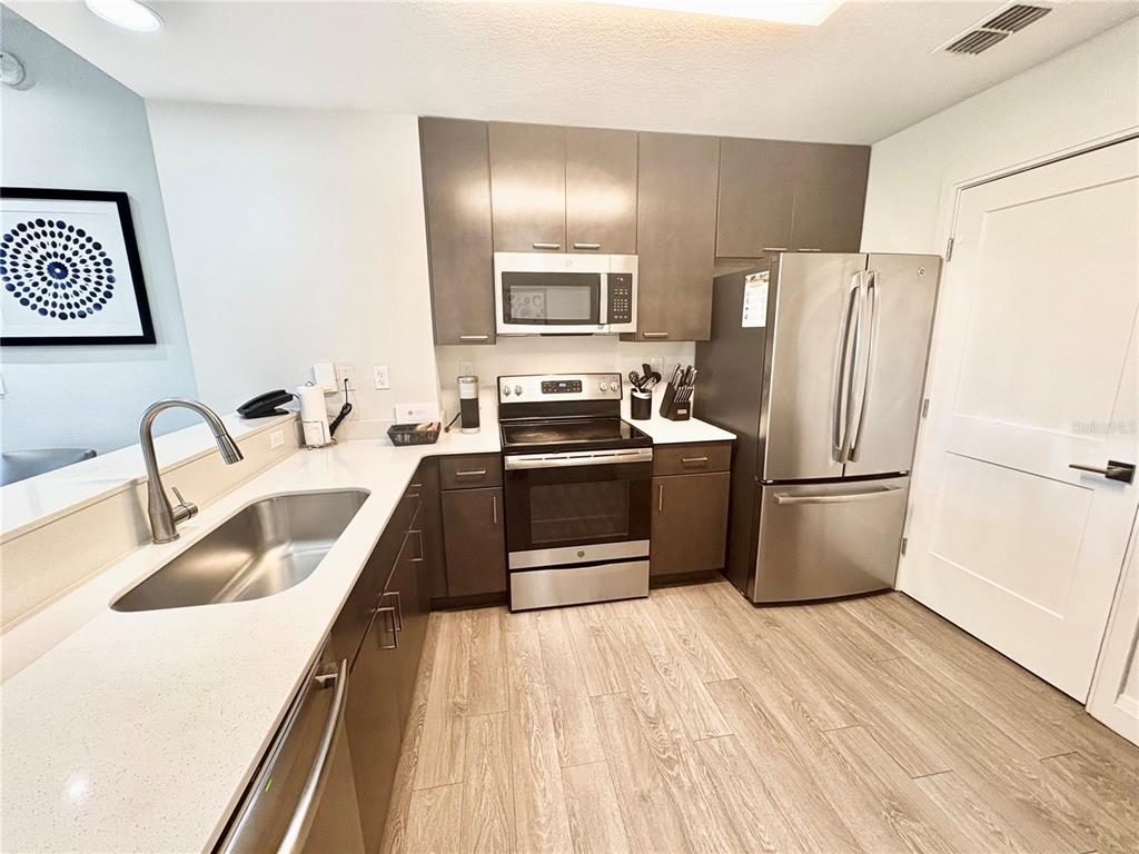 A kitchen features dark wood cabinets, stainless steel appliances, and light-colored countertops — 14501 GROVE RESORT AVENUE UNIT 3524, WINTER GARDEN, FL