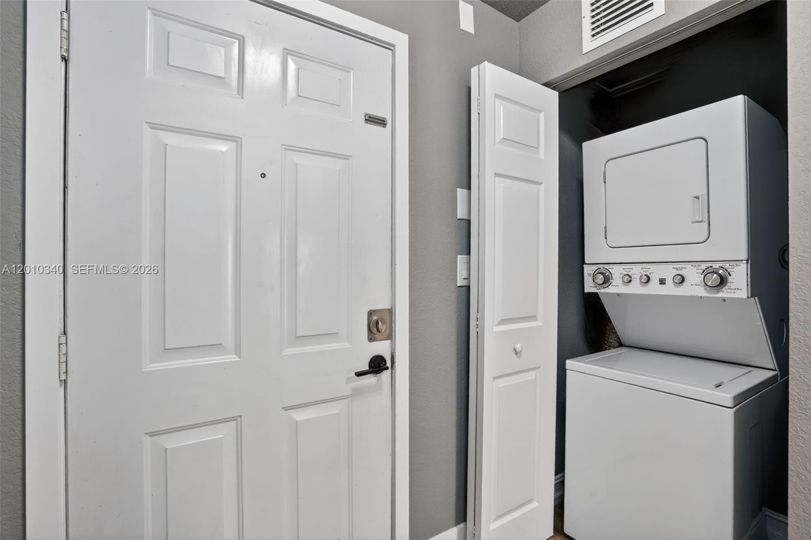 A white front door stands next to a closet containing a stacked washer and dryer — 7995 NW 8th St # 100C, Miami FL 33126, MIAMI, FL