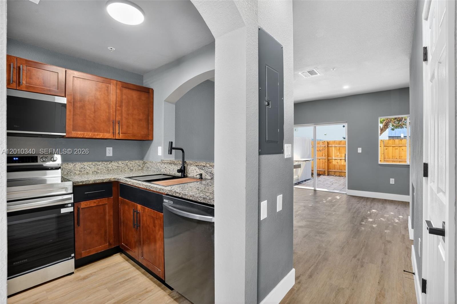 A kitchen with wood cabinets and stainless steel appliances opens into a living area — 7995 NW 8th St # 100C, Miami FL 33126, MIAMI, FL