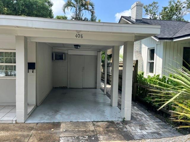 A covered carport with a concrete floor and a white exterior stands beside a house — 408 HOLT AVENUE, WINTER PARK, FL