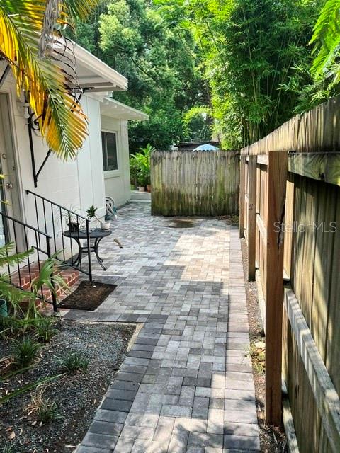 A paved patio area sits beside a white house and a wooden privacy fence — 408 HOLT AVENUE, WINTER PARK, FL